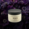 Jar of 'Black Chamomile' body butter on a dark floral background