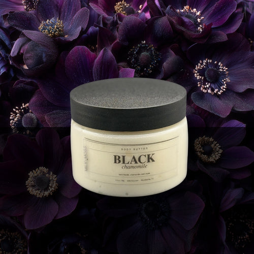 Jar of 'Black Chamomile' body butter on a dark floral background