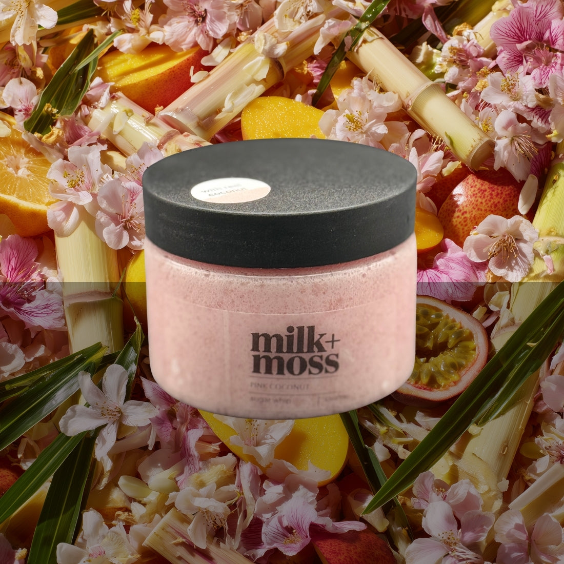 Pink jar with black lid labeled 'milk+moss' surrounded by tropical fruits and flowers