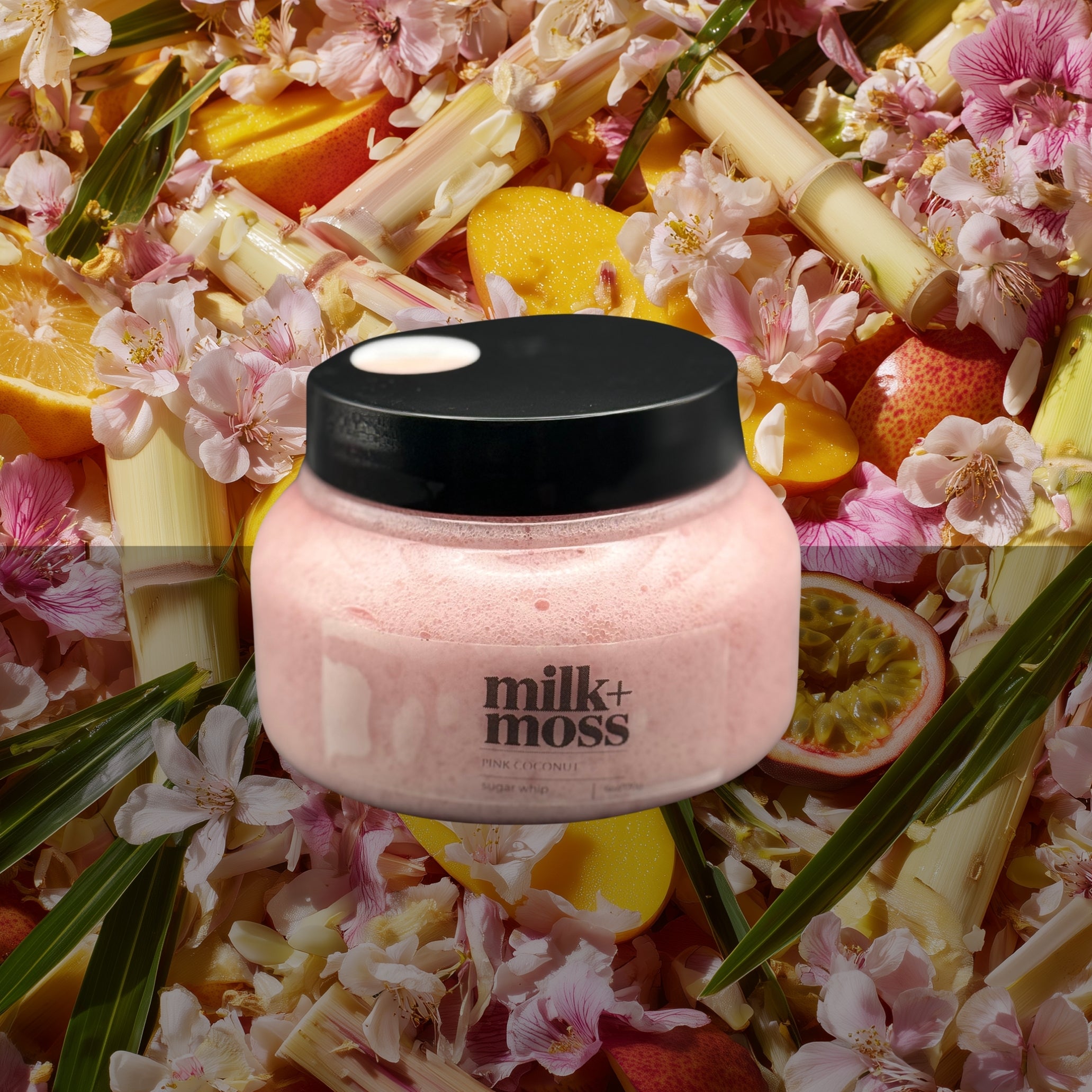 Pink jar with black lid labeled 'milk+moss' surrounded by tropical fruits and flowers